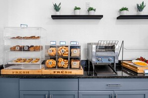 A kitchen counter with a fresh bakery display, a toaster, and a bowl of strawberries. - Close to Disney World Resort + Free Breakfast (Kissimmee)