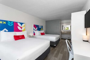 Ein Hotelzimmer mit zwei Betten, einem Schreibtisch und einem Badezimmer.