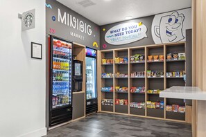 A snack bar with a Coca-Cola cooler, shelves stocked with snacks, and a wall with a 'What do you need today?' sign. - Near Disney World Resort + Free Shuttle. Breakfast (Kissimmee)