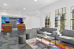 A modern hotel lobby with a reception desk, two sofas, a coffee table, and a colorful rug. - Near Disney World Resort + Free Shuttle. Breakfast (Kissimmee)