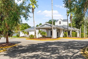A single-story building with a covered porch, surrounded by palm trees and a well-maintained lawn. - Near Disney World Resort + Free Shuttle. Breakfast (Kissimmee)
