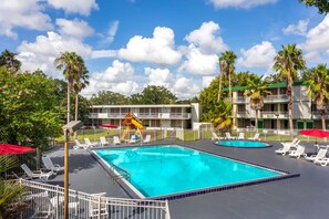 Ein Swimmingpool mit Rutsche, umgeben von Liegestühlen und Palmen.