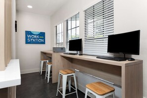 A work station with two monitors, a keyboard, and a projector. There are three white stools and a white desk. - Mins to Disney World Resort + Free Shuttle & Pool (Kissimmee)