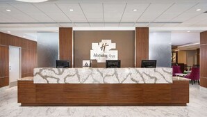 A reception desk with a marble top, two monitors, and a Holiday Inn sign. - Stay Near UMD | Wi‑Fi, Pool, and Restaurant (College Park)