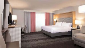 A hotel room with a bed, a desk, a chair, a TV, and a window with curtains. - Stay Near UMD | Wi‑Fi, Pool, and Restaurant (College Park)