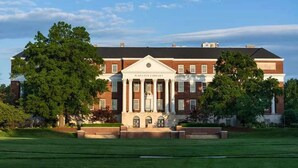 A large brick building with a central portico and columns, surrounded by a well-maintained lawn. - Stay Near UMD | Wi‑Fi, Pool, and Restaurant (College Park)