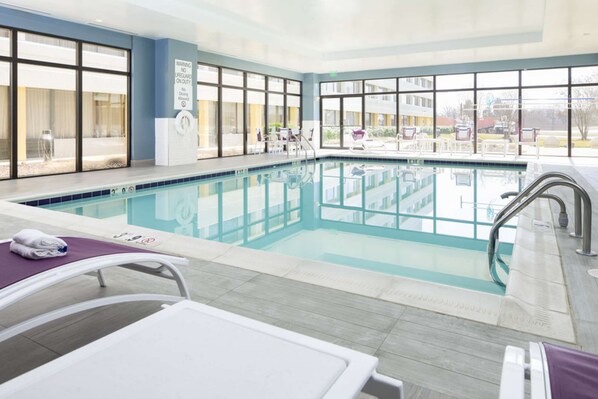 Ein Hallenbad mit großen Glaswänden, einer Rettungswachen und Liegestühlen.