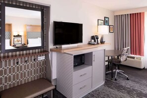 A hotel room with a bed, a TV, a desk with a chair, a microwave, and a window with curtains. - Stay in College Park | Group‑Friendly. Pool. Bar. (College Park)
