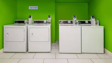 A laundry area with three washing machines and a sign indicating it's for guests.