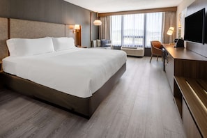 A hotel room with a large bed, a desk, a chair, a flat-screen TV, and a window with curtains. - King Room Near Columbia | Wi‑Fi, Pool, & Dining (Jessup)
