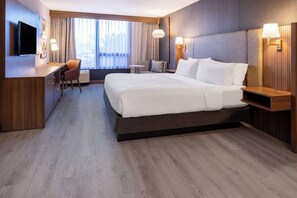 Una habitación de hotel con una cama grande, mesitas de noche, un escritorio, una silla y un televisor.
