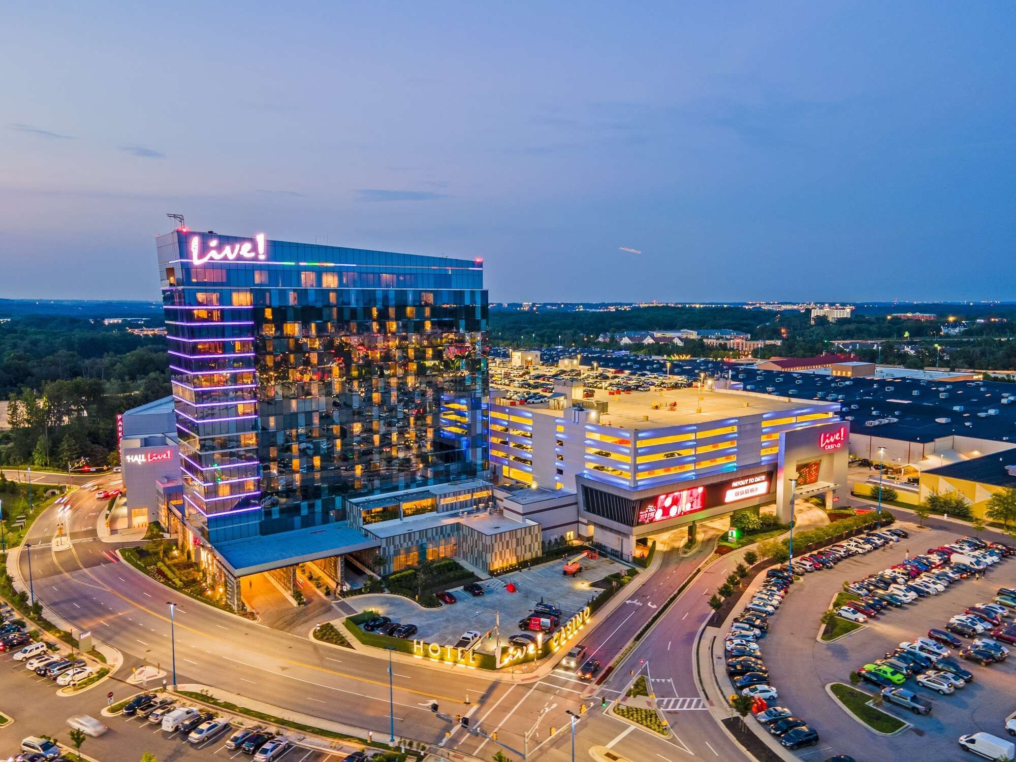 Un hotel de varios pisos con un llamativo letrero 'Live!', un estacionamiento y un casino.