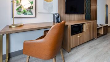 Una cocina moderna con encimera de madera, microondas integrado y televisor de pantalla plana en la pared.