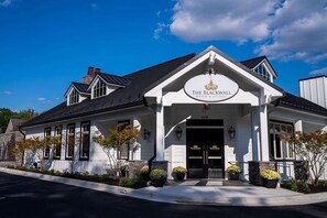 A white building with a black roof, a sign reading 'The Black Wall Barn & Lodge,' and a number '329' above the entrance.