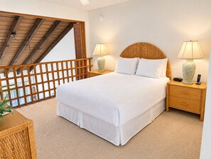 Ein Schlafzimmer mit einem großen Bett, zwei Nachttischen mit Lampen, einem Holzkopfende und einem Balkon mit Holzbalkon.
