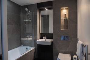 A modern bathroom with a bathtub, a glass-enclosed shower, a sink, and a toilet. - Spacious Woolwich Apartment With sea View (London)