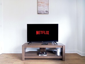 Een televisie op een houten standaard, met afstandsbediening en een boek met de titel 'Selling to Serve'.