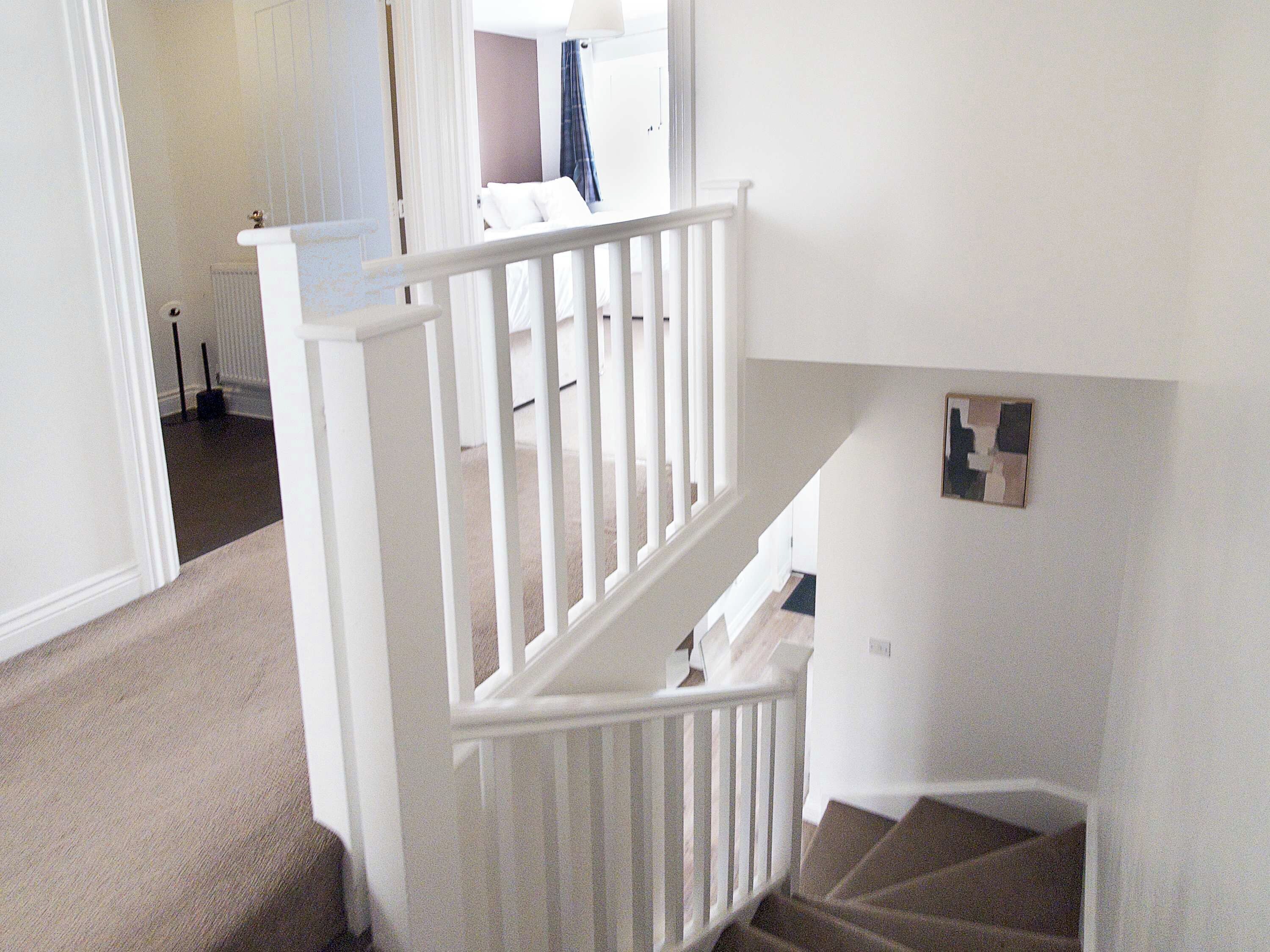 Eine Treppe mit weißen Geländern, die zu einer oberen Etage führt.
