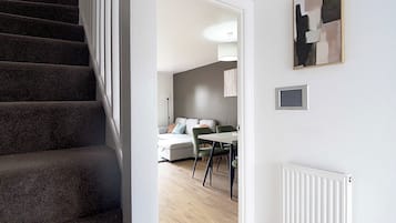 A staircase leading to a room with a dining area, a radiator, and a framed artwork on the wall.