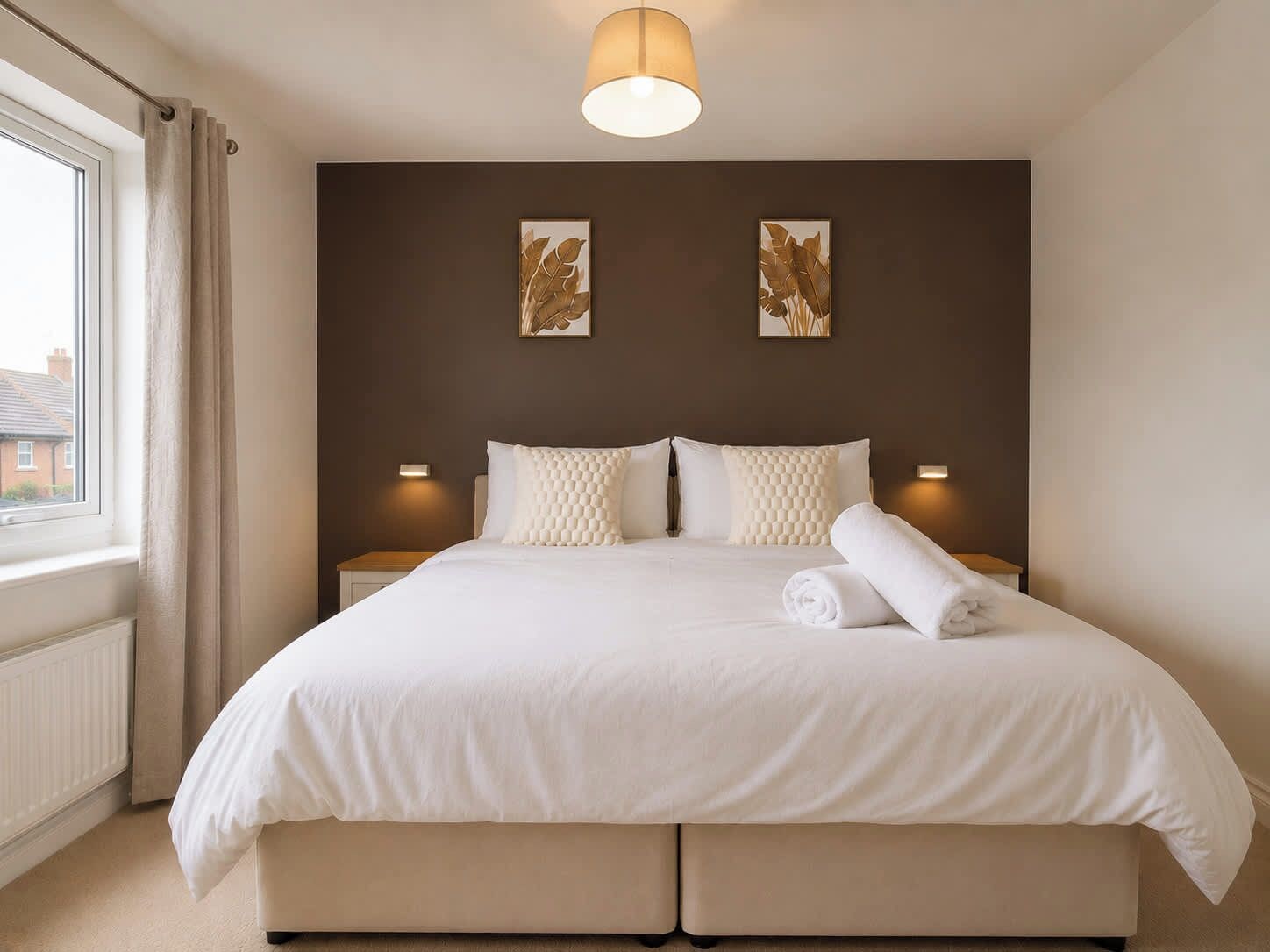 Ein Hotelzimmer mit einem großen Bett, zwei Wandleuchten und zwei gerahmten Kunstwerken an der Wand.