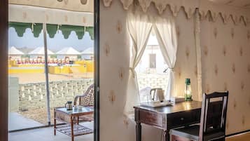 A room with a dining table, chairs, and a view of an outdoor area with yellow structures.