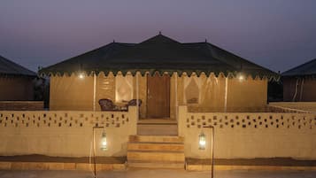 A tent-like structure with a door and steps leading up to it, surrounded by a low wall with lanterns.