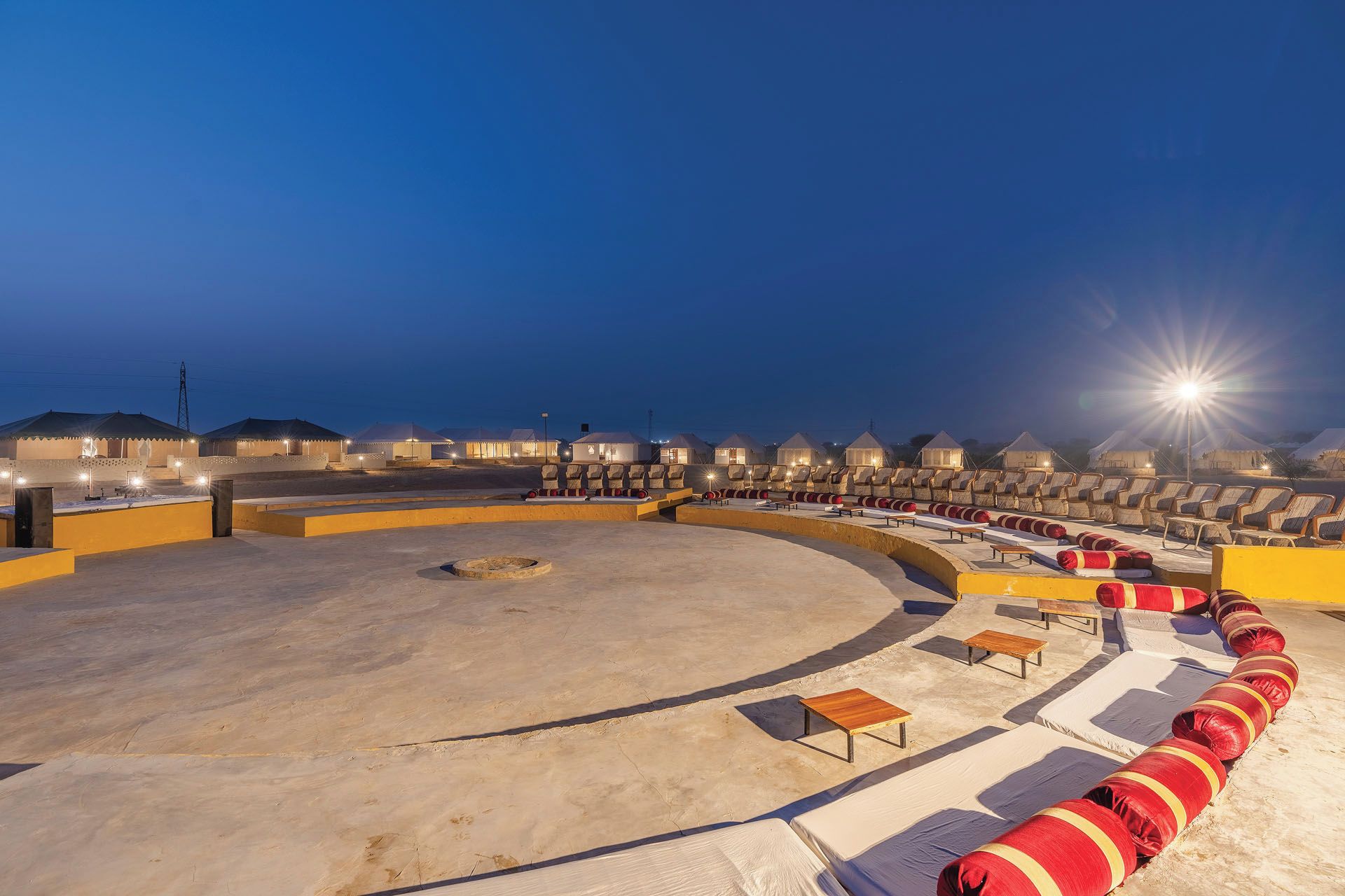 Un gran anfiteatro al aire libre con asientos escalonados, un escenario y una fila de sillas de playa.