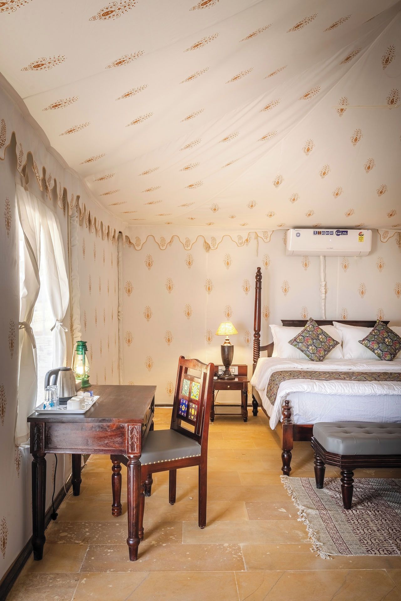 A hotel room with a bed, a table with a chair, a lamp, and a radiator.