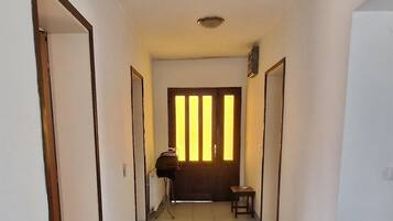 A hallway with a tiled floor, a door on the left, a bench in the center, and a door on the right.