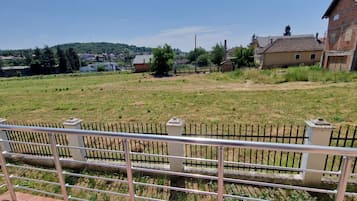Un espace extérieur clos, avec un terrain herbeux, un bâtiment doté d’un toit rouge et un ciel dégagé.