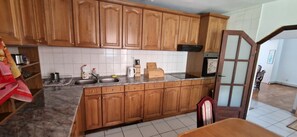 A kitchen with wooden cabinets, a sink, a stove, and a dining area with a table and chairs.