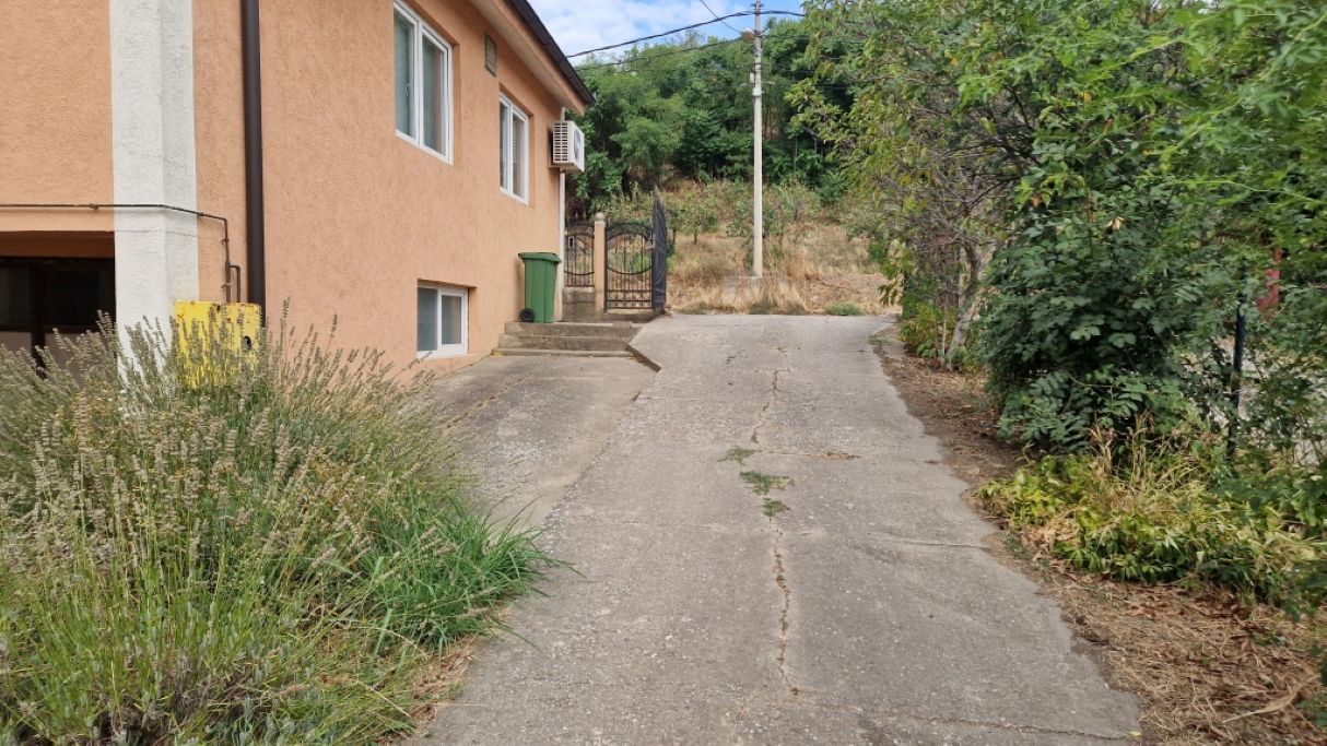 A narrow paved path leading to a building with a gated entrance.