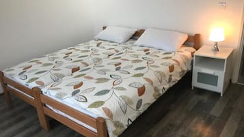 Ein Einzelbett mit einem blattgemusterten Überwurf, ein Nachttisch mit einer Lampe und ein weiterer Nachttisch.