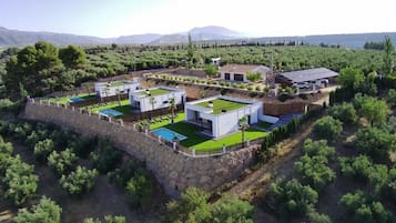 Zona residencial amb diverses cases modernes, una piscina i una paret de pedra.