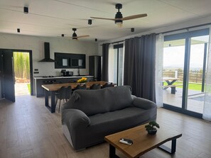 A modern living room with a sofa, coffee table, and a view of the outdoors.