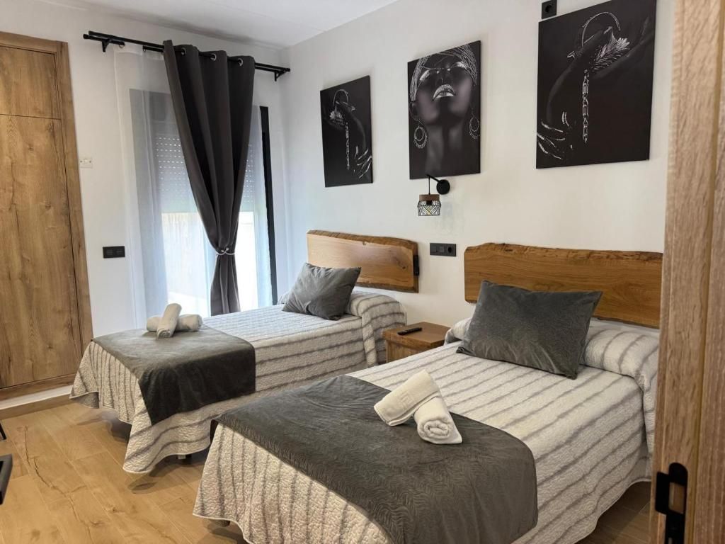 Una habitación de hotel con dos camas, un cabecero de madera y obras de arte en las paredes.