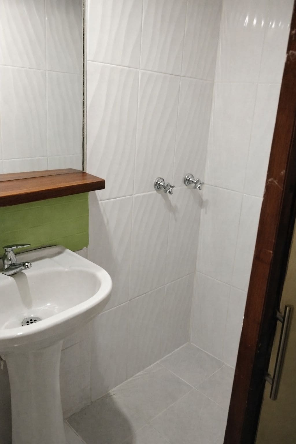 A bathroom with a white sink, green countertop, and white tiled walls.