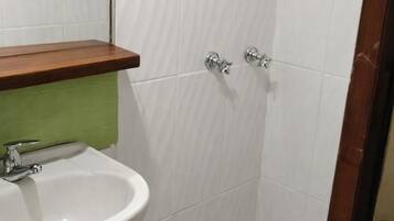 A bathroom with a white sink, green countertop, and white tiled walls.