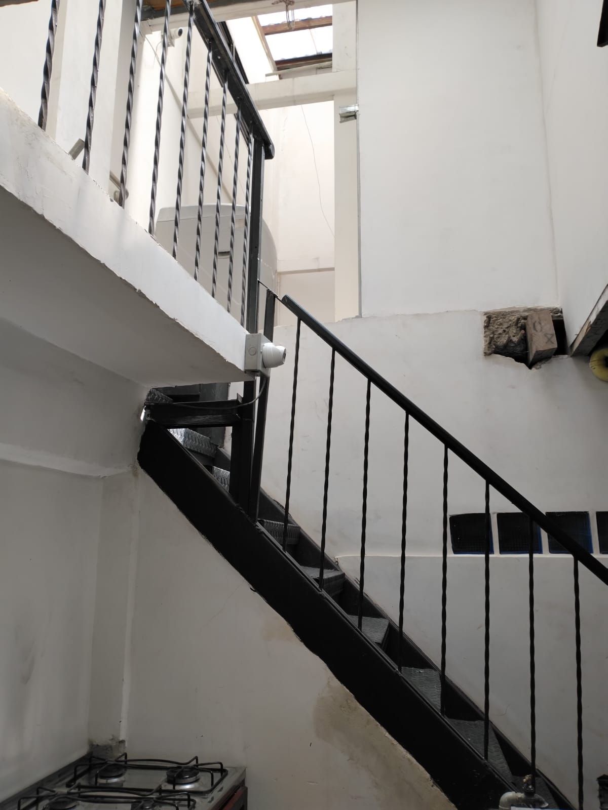 A staircase with a black handrail and white walls, leading to an upper floor.