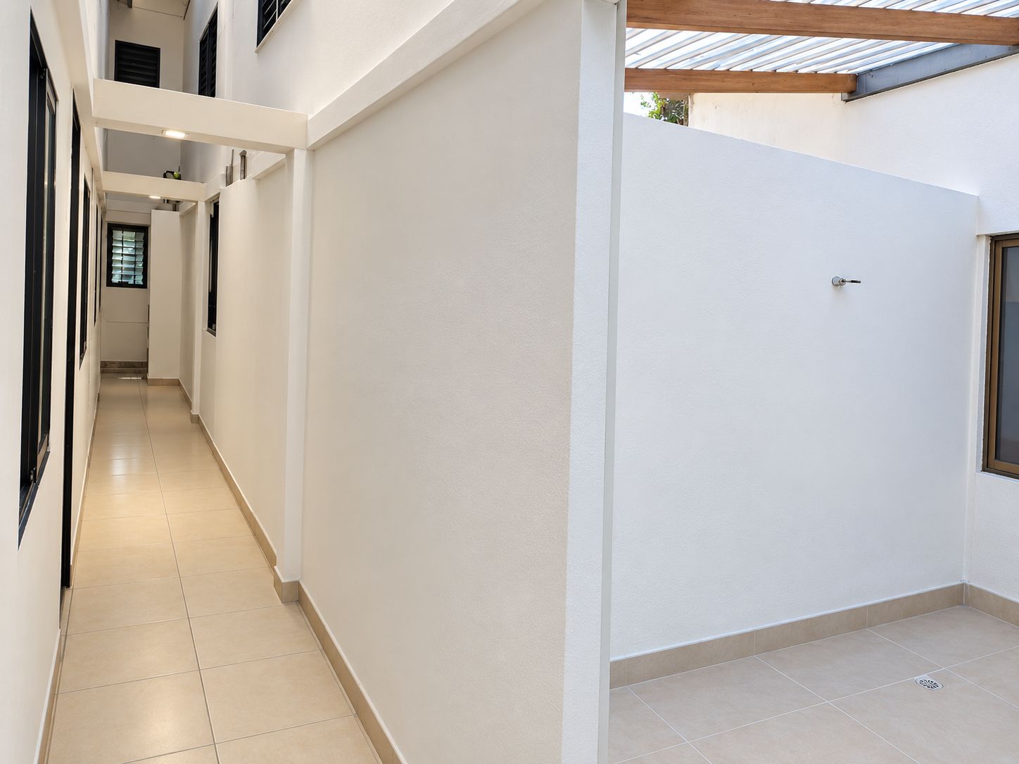 A corridor with a tiled floor, white walls, and a door with a window.