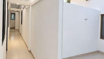 A corridor with a tiled floor, white walls, and a door with a window.