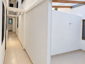 A corridor with a tiled floor, white walls, and a door with a window. - Apto duplex con vista a la calle (Medellin)
