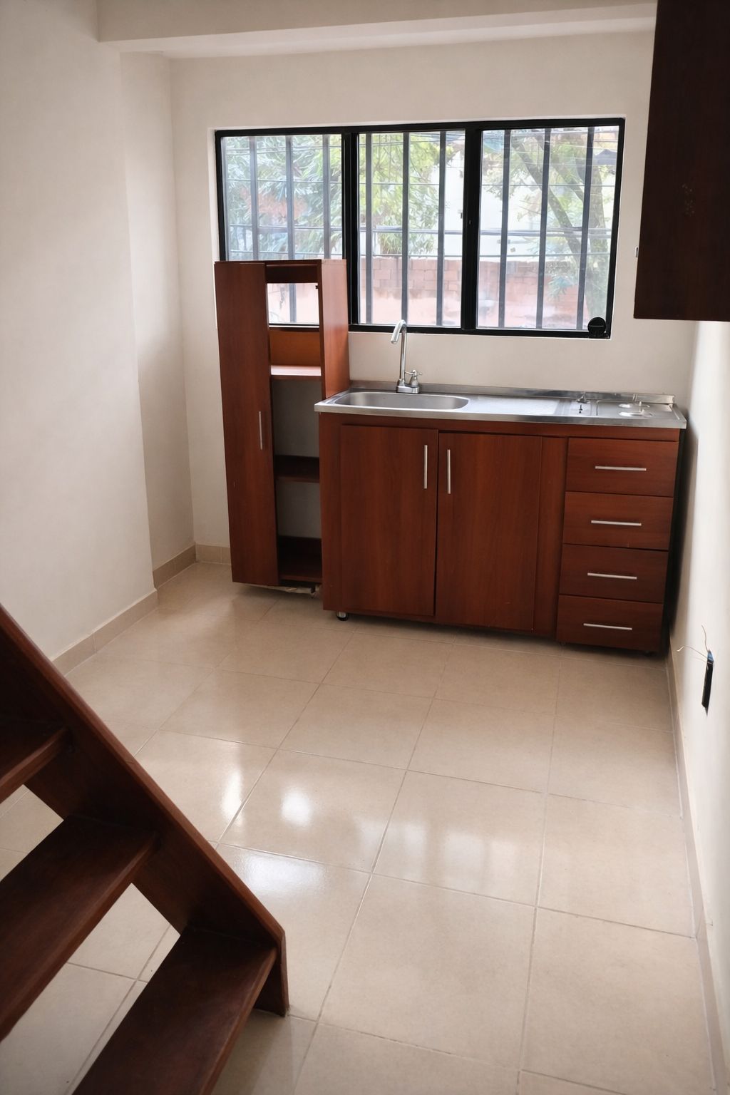 A kitchen with a built-in sink, wooden cabinets, and a window with a view of trees.
