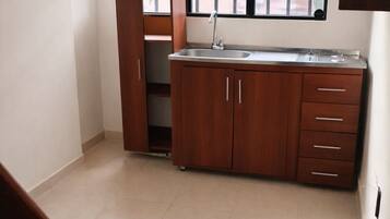 A kitchen with a built-in sink, wooden cabinets, and a window with a view of trees.