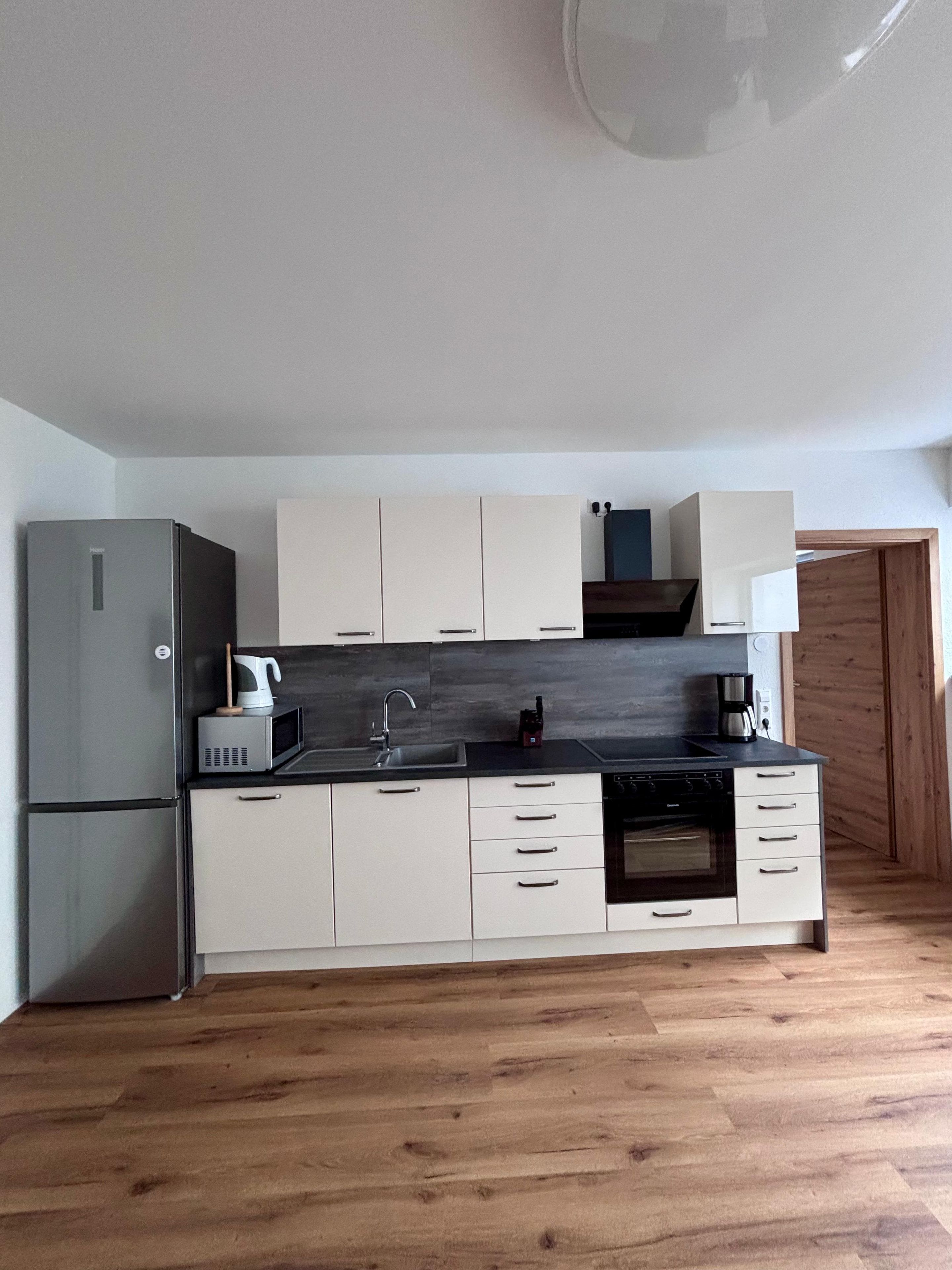 A compact kitchen with a refrigerator, microwave, sink, and stove.