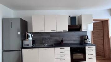 A compact kitchen with a refrigerator, microwave, sink, and stove.