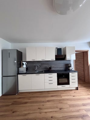 A compact kitchen with a refrigerator, microwave, sink, and stove.