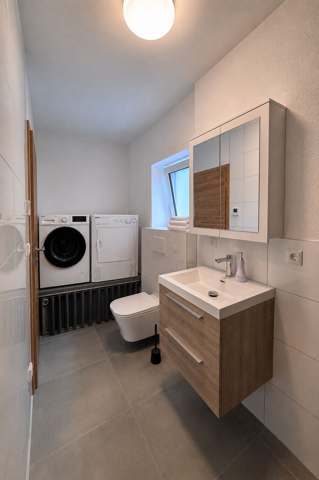 Ein modernes Badezimmer mit Waschmaschine, Toilette und Waschtisch mit Spiegel.