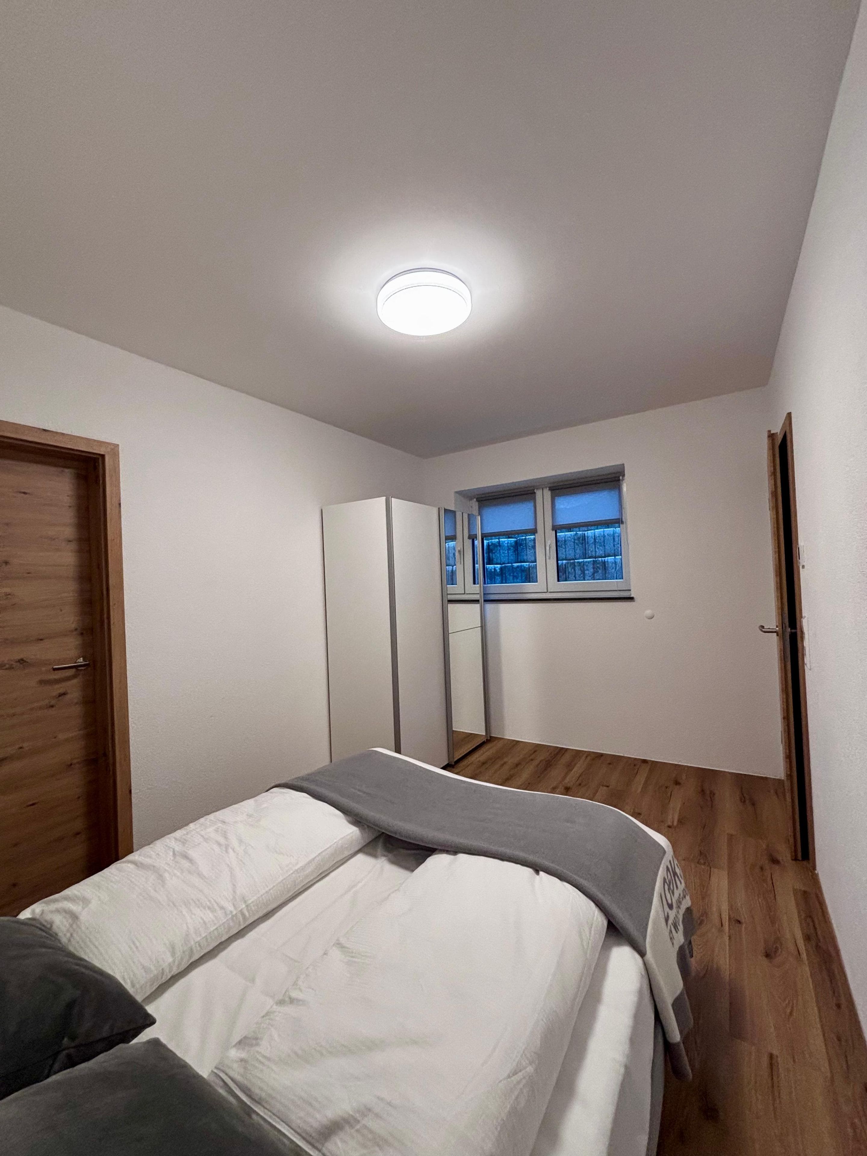 Un dormitorio con una cama, ventana, armario y puerta.