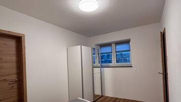 Un dormitorio con una cama, ventana, armario y puerta.